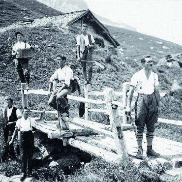 Ein Buch gegen das Vergessen - Eines der 400 Fotos aus dem Buch: die alte Brücke über den Tungelbach auf Chüetungel, im Hintergrund ein Weidestall, der abgebrochen wurde. Vorne stehend auf der Brücke Christian Schwizgebel (geb. 1903), rechts daneben sitzend Arnold Brand, Graben, hinten links mit Handorgel Christian Brand im Baumgarten (geb. 1903) und hinten rechts Albert Hefti (geb. 1903). Das Foto ist aus den 1920er‑Jahren. FOTO: RUTH‑ANNEN BURRI