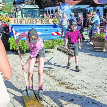 Von der Alp ins Dorf: Fotostrecke Gstaad Züglete 2023 - Das Kuhfladen-Mobil mit seinen fleissigen Helfenden.