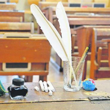 Schulstunden wie vor 100 Jahren - Das Lehrerpult. Man erkennt Federn, Kreide, Tinte und das Tintentuch, das jeweils die Mädchen im Handarbeitsunterricht für die ganze Klasse hergestellt hatten.