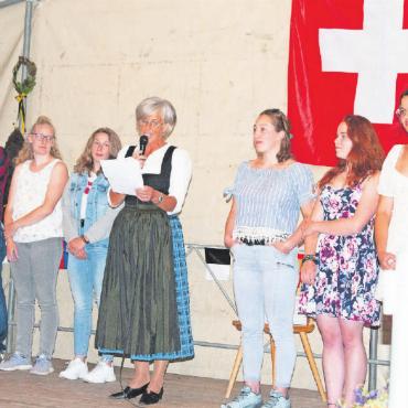 «Die Flagge ist ein grosses Plus» - Gespannt erwarten die Jungbüger:innen der Gemeinde Lauenen ihren Jungbürgerbrief, während Gemeindepräsidentin Ruth Oehrli ihnen ihre besten Wünsche mit auf den Weg gibt. FOTO: KEREM MAURER