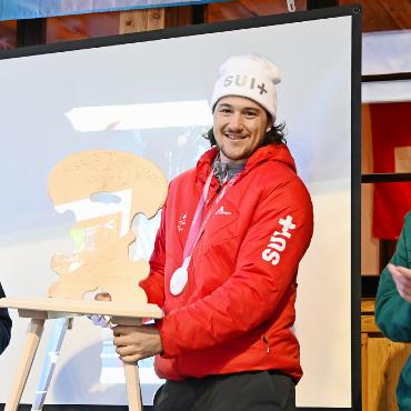 Willkommen zurück, «Silber-Fäbu»! - Einen eigens für ihn angefertigten Stuhl, oder genauer gesagt eine Stabelle mit Gravur, nahm Fabrice von Grünigen vom Skiclubpräsident Chrigel Müllener(links) entgegen.    FOTOS: JENNY STERCHI