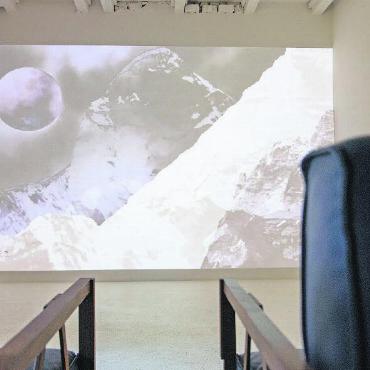 Schlichte Kunst mit bedeutungsvollem Hintergrund - Was wäre eine Multimediaausstellung ohne eine Videoinstallation mit Musik? Die Besuchenden können es sich auf den Stühlen bequem machen, den Geräuschen und der Musik zu hören, und die Bilder auf sich wirken lassen.