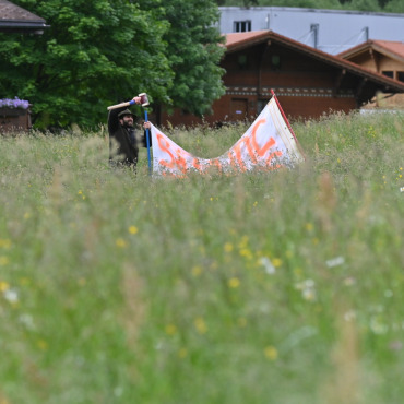 Die Heuernte als Gefahrenzone für Rehkitze - Jungjäger Sandro Zumbrunnen verschwindet bis zur Hälfte im hohen Gras, um das Tuch aufzuspannen, das Rehgeiss und Kitz sanft aus der Wiese drängen soll.    (Fotos: Jenny Sterchi)