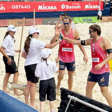 Schweizer Donnerstag am Swatch Beach Pro Gstaad - Marco Krattiger und Leo Dillier nach ihrem siegreichen Auftakt am Mittwoch. Ballkinder und «Sandrecheler» gratulierten, wie es im Beachvolleyball gebräuchlich ist.