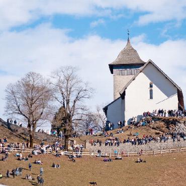 Schönes Wetter ist nicht gleich Flugwetter - Die Zuschauenden haben bei der Kirche Platz genommen, um das Spektakel zu verfolgen.