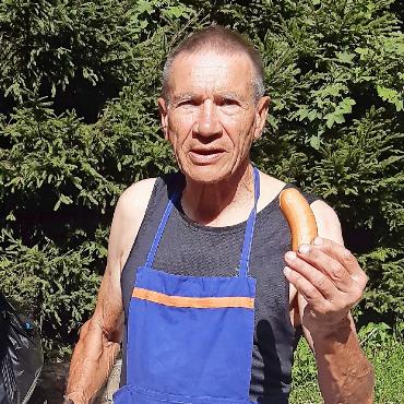 Heimwehsaaner:innen versammelten sich zum Brätliabend - Housi ist der Grillmeister mit der Bratwurst in der Hand.