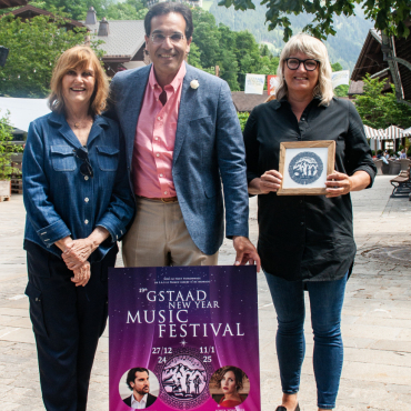 Frischer Wind und neuer Auftritt - Prinzessin Caroline Murat (links), künstlerische Leiterin und Gründerin des Gstaad New Year Music Festivals, mit Çetin Köksal, administrativer Leiter, mit dem neuen Plakat. Regina Martin (rechts)  kreierte den  Scherenschnitt für das neue Logo. (Foto: AvS)