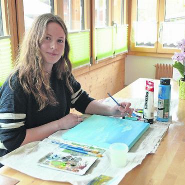 Inspiriert vom Leben und der Natur - Melinda Brand arbeitet kreativ am Esstisch. Hier malt sie mit Acrylfarben Wolken. Sie mag diesen Platz, weil es dort am meisten Sonnenlicht gibt. FOTOS: NICOLAS GEISSBÜHLER