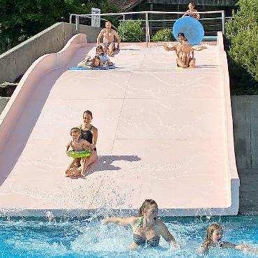 Rutschbahnstart mit «Franjo-Hube» - Salome und Ramona sind die ersten im 15 Grad kalten Wasser. Auf der Rutschbahn: hinten links Marco, Liana und Anais auf dem Brett, vorne Angela mit Livio, hinten rechts Melina mit Brett, Andreas mit «Franjo-Hube» und Lukas. FOTO: ZVG