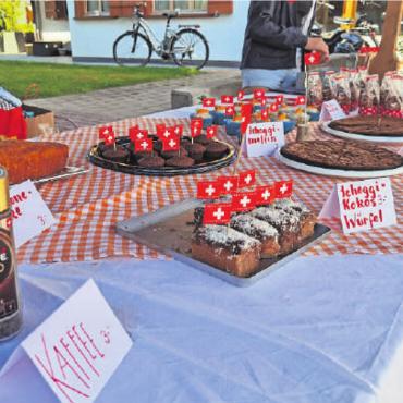 Freudige Dorffeier zu Ehren des Schweizer Geburtstages - Schweizer Fähnchen auf dem Kuchen sind ein Muss.