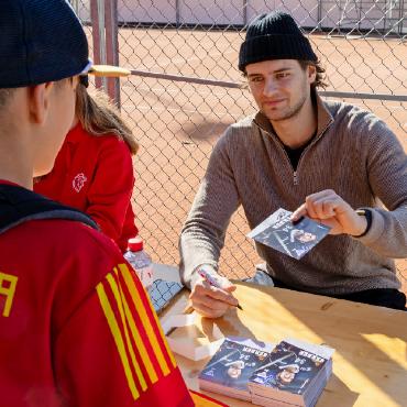 Gemeinsam macht es mehr Spass! - Jeremi Gerber vom HC Fribourg-Gottéron übergibt einem Fan die gefragte Autogrammkarte.
