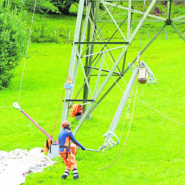 Sanierung in luftiger Höhe - Der neue Isolator aus Kunststoff wird mithilfe einer Seilwinde vorsichtig nach oben gezogen. FOTO: JONATHAN SCHOPFER