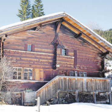 Lebendiges Kulturerbe: Wie das Saanerhaus zu seiner Hausform kam - Das vermutlich in den 1450er-Jahren erbaute Heidenhaus in der Lauenen – so genannt wegen des Heidenkreuzes an der Giebelwand – ist das älteste Haus des Saanenlandes. Im Kreis rechts: Das gotische Spitzbogenmotiv des Türsturzes über der Eingangstür ist typisch für diese Bauepoche.   FOTOS: MARTIN GURTNER-DUPERREX