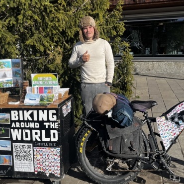Mit dem Fahrrad um die Welt - Samt Stand und Fahrrad steht Winmar vor der Kapelle Gstaad und verkauft seine Fotografien und  hausgemachten Kekse. (Fotos: Paula Mittag)
