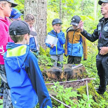 Unterwegs im Wald mit dem Ferienpass - Oder man formt auf dem «Scharnier» eines gefällten Baumes ein Dreieck, um zu sehen, in welche Richtung der Holzer den Baum fallen liess.