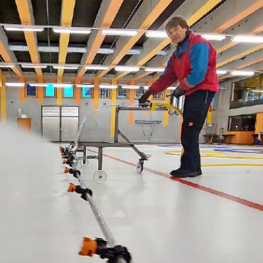 Kunsteis – eine ganze Menge Wasser und viel Arbeit - 1 Mit dem Sprühbalken wird der Betonboden mit Wasser bespritzt, das sogleich gefriert. Durch mehrmalige Wiederholung des Vorgangs wird er versiegelt.