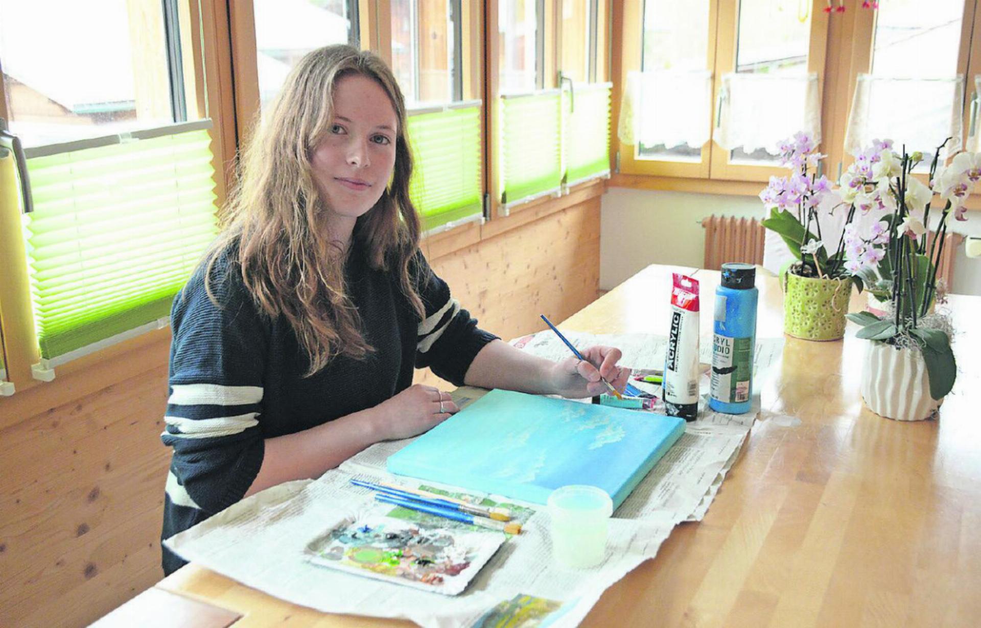 Melinda Brand arbeitet kreativ am Esstisch. Hier malt sie mit Acrylfarben Wolken. Sie mag diesen Platz, weil es dort am meisten Sonnenlicht gibt. FOTOS: NICOLAS GEISSBÜHLER