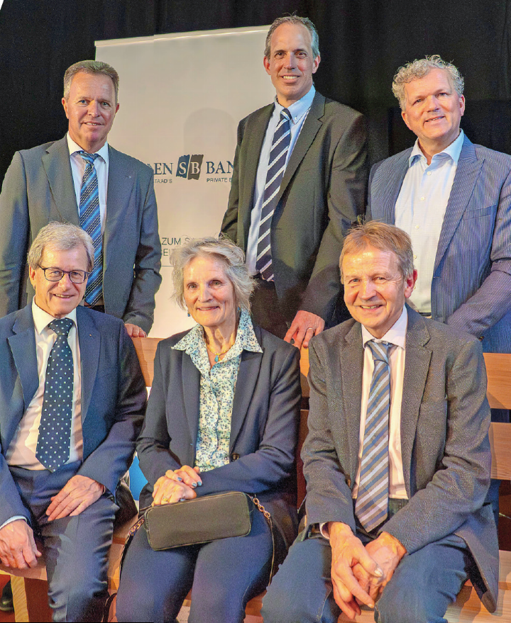 Auf der hölzernen Sitzbank – einem Geschenk für sein langjähriges Engagement – nimmt der abtretende Verwaltungsratspräsident Victor Steimle Platz (links). Neben ihm sitzen Regula van der Velde (austretendes Verwaltungsratsmitglied) und Erich von Siebenthal (wiedergewähltes Verwaltungsratsmitglied). Dahinter stehen Jürg von Allmen (CEO), Daniel Matti (designierterVerwaltungsratspräsident) undFelix Graber (neugewähltesVerwaltungsratsmitglied). Brigitte Hoefliger-von Siebenthal fehlte aufgrund eines länger geplantenFamilienurlaubs, wie Steimle an der GV erklärte.   FOTOS: JOCELYNE PAGE