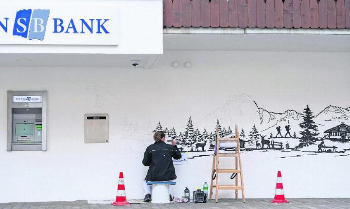 Karin Hänni, Dekorationsmalerin, bei der Arbeit. Sie verwandelte die Bankfassade in Saanen zu einem echten Hingucker. FOTO: CORINNA MÜLLER, SAANEN