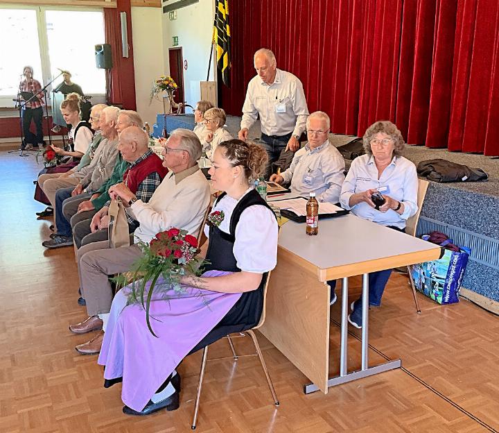 Hinter den Tischen sitzt der Vereinsvorstand, vor den Tischen die Jubilare 90 , eingerahmt von den beiden Ehrendamen.