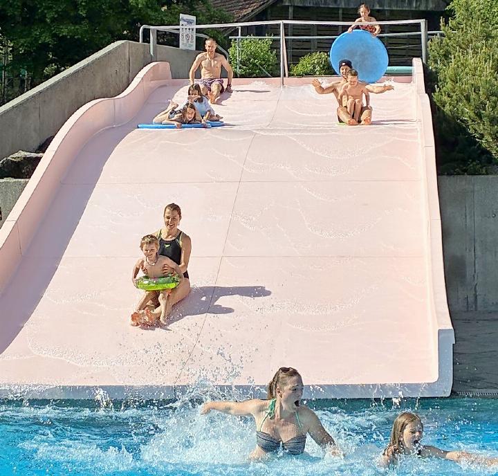 Salome und Ramona sind die ersten im 15 Grad kalten Wasser. Auf der Rutschbahn: hinten links Marco, Liana und Anais auf dem Brett, vorne Angela mit Livio, hinten rechts Melina mit Brett, Andreas mit «Franjo-Hube» und Lukas. FOTO: ZVG
