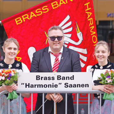 Zwei Topplatzierungen am EMF 2026 für die Brass Band «Harmonie» Saanen und die Musikgesellschaft Gstaad - Der Dirigent der BBHS, Michael Bach, gesäumt von den Ehrendamen, konnte sich mit seinem Verein über den dritten Schlussrang in der 2. Klasse Brass Band freuen.   FOTOS: RTR/DOMINIC POHLE
